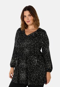 Black long-sleeve top featuring a V-neck, dotted white pattern, gathered waist, and elastic cuffs. Made of lightweight, soft fabric.