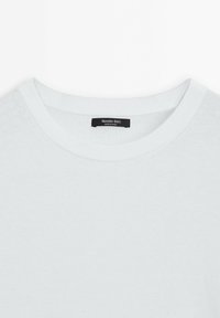 Ljusblå crewneck-tröja med ribbad halsringning och subtil textur. Etiketten säger "Massimo Dutti, tillverkad i Kina." Enkel, minimalistisk design.