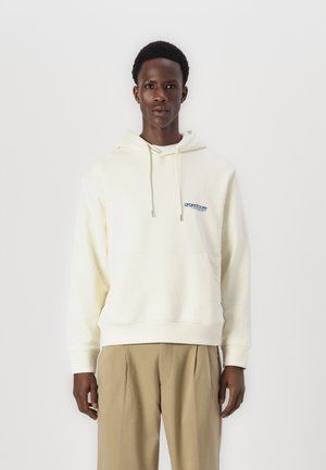 Crème kleurige hoodie van zacht materiaal, voorzien van een trekkoord capuchon en een voorzak, met een blauw logo op de linkerborst.