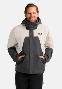 Waterdichte jas in lichtgrijs en donkergrijs. Voorzien van een hoge kraag, dubbele zijzakken en logodetails. Duurzame stof en een ontspannen pasvorm.