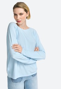 Hellblaue, langärmelige Pullover aus weichem Stoff, mit rundem Ausschnitt und lässiger Passform, kombiniert mit hellblauen Jeans.