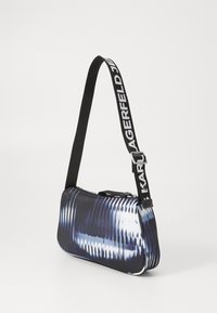 Borsa a tracolla con un motivo astratto nero e blu, chiusura con zip e tracolla nera regolabile con testo bianco. Materiale sintetico liscio.
