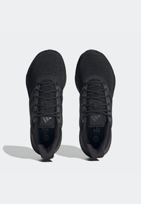 Zapatillas deportivas negras con una parte superior de malla texturizada, cordones planos y acentos de tres rayas. Presentan una suela acolchada y un diseño ergonómico.