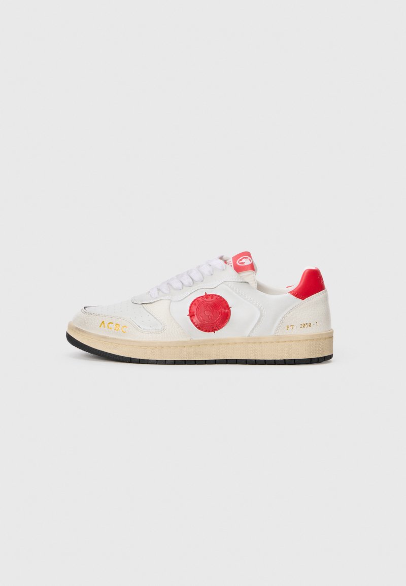 Hvide sneakers med røde detaljer, glat læderoverdel, tekstureret logo på siden, hvide snørebånd og en sort gummisål.
