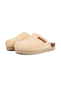 Chaussons en cream moelleux avec une texture douce, semelle en caoutchouc beige et un accent de logo marron sur le côté. Design à enfiler, sans dos.