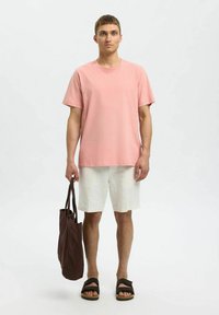 Ljusrosa bomulls t-shirt, rund hals, korta ärmar, parat med vita linnebyxor. Brun tygväska och svarta sandaler.