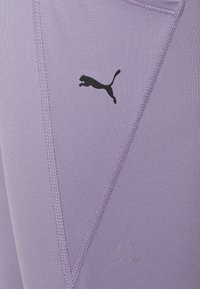 Laventeli urheiluleggingsit, jotka on valmistettu sileästä, joustavasta kankaasta. Niissä on musta Puma-logo ja kontrastoivat saumat lisäyksinä.