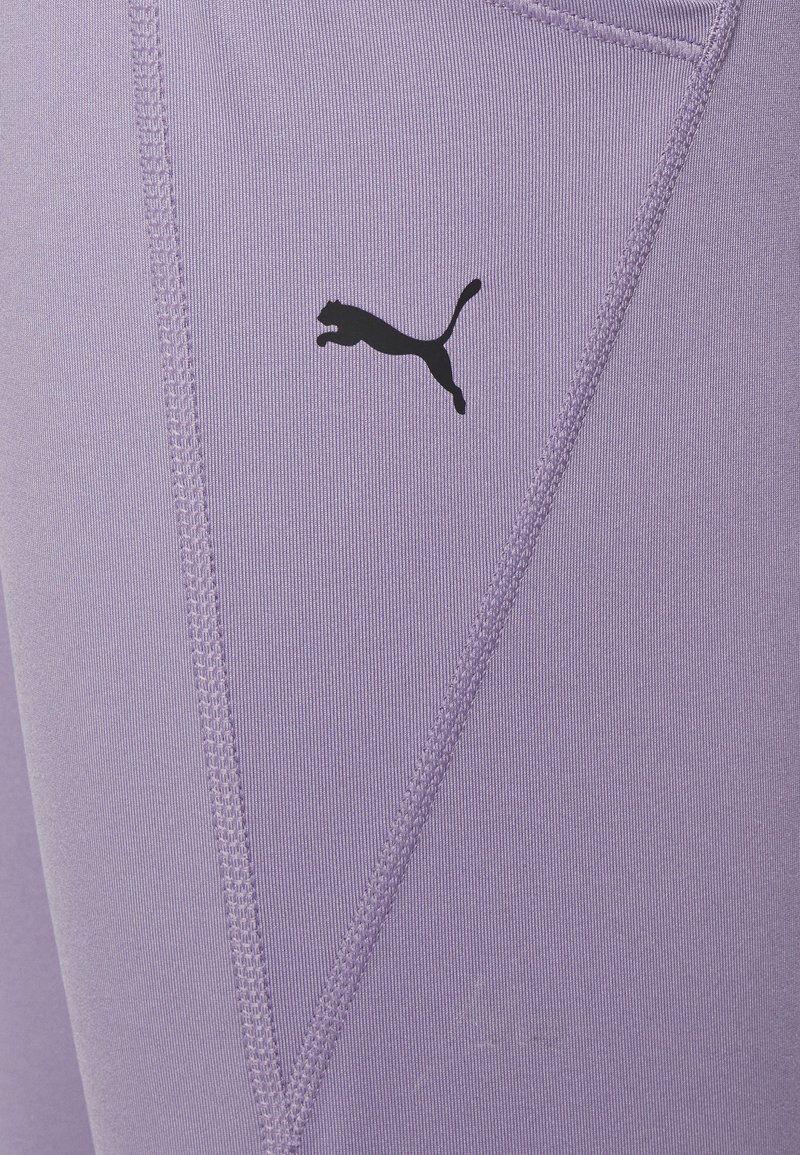 Lavendel sportieve leggings gemaakt van een gladde, rekbare stof, met een zwart Puma-logo en contrasterende stiksels voor extra detail.