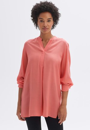 Korallefarbene Bluse mit langen Ärmeln und V-Ausschnitt, lockerer Schnitt und umgeschlagenen Bündchen, aus leichtem Stoff mit glatter Textur und seitlichen Schlitzen.