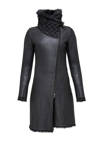 Crni kožni kaput s asimetričnim zatvaranjem na munjac, teksturiranim krznim ovratnikom i krznom na rubovima rukava i donjem rubu. Elegantnog je, prilagođenog dizajna.