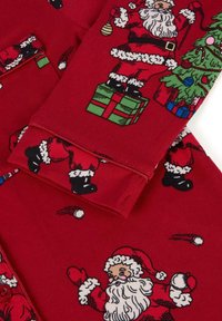 Roter Stoff mit festlichen Motiven von Santa Claus, Weihnachtsbaum, verpackten Geschenken und Weihnachtsornamenten in einem sich wiederholenden Muster.