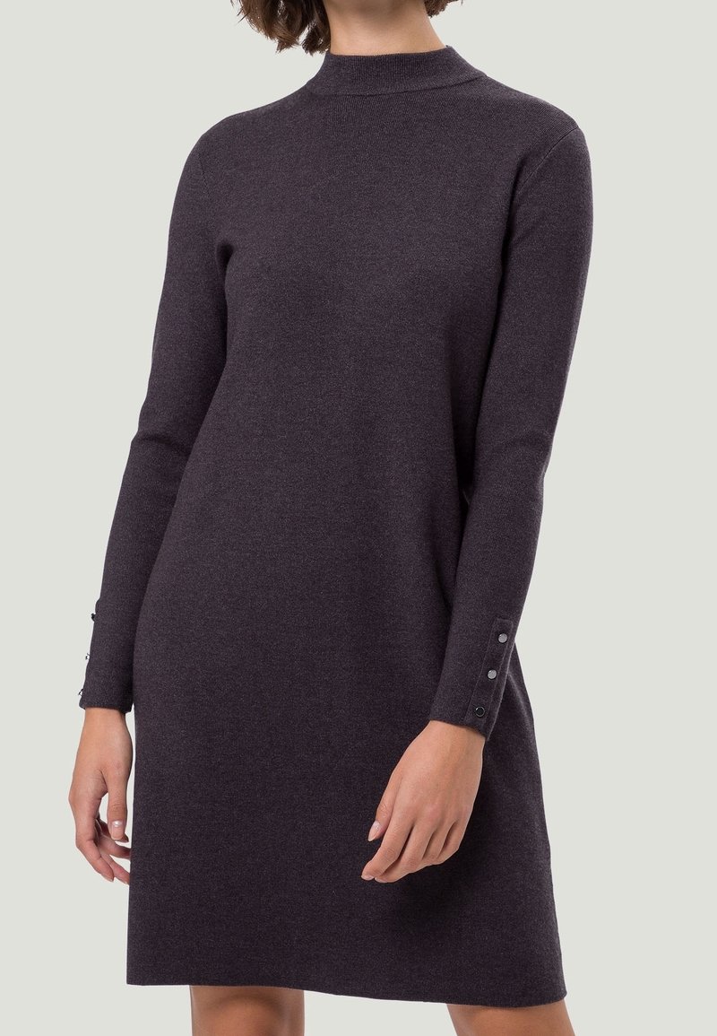 Robe tricot à manches longues en gris foncé avec un col haut, présentant des accents de boutons aux poignets pour un effet de détail. Texture lisse et silhouette ajustée.
