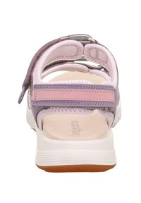 Zadní pohled na sandál, který má bílou podrážku, růžové a levandulové popruhy, měkké polstrování a nastavitelné uzávěry na suchý zip pro pohodlí.