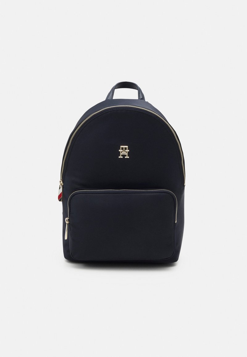 Sac à dos en nylon noir avec des zippers dorées, poche zippée à l'avant et petit logo doré en haut au centre.