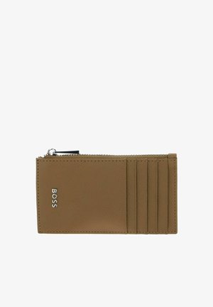 Portefeuille en cuir fauve avec fermeture éclair, comprenant quatre emplacements pour cartes et un détail logo. Texture lisse avec un design minimaliste.