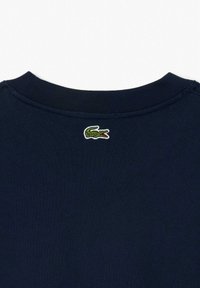 T-shirt in cotone blu navy con scollatura rigata e piccolo logo di coccodrillo verde ricamato sul retro. Texture liscia.