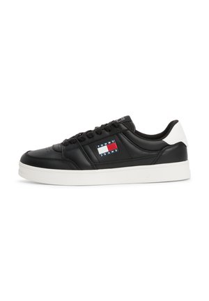 Black leather sneaker with white sole, lace-up front, and logo patch featuring red, white, and blue stripes on the side.
