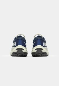 Baskets de course navy avec une semelle texturée, épaisse en blanc et noir, un col rembourré et des accents réfléchissants sur le talon et sur le côté.