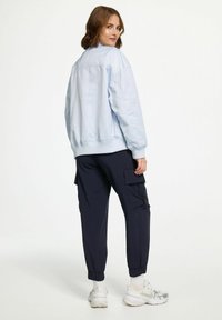 Light blue bomber jacket with ribbed cuffs and hem, paired with navy cargo pants featuring side pockets and elastic ankle cuffs.