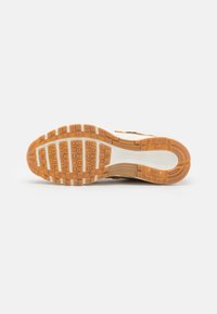 Nike tenisica s potplatom od smeđeg gume s uzorkom za bolju prianjivost. Sadrži bijeli međupotplat i vidljivi logo branda na peti.