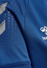 Blauw sportshirt van een gestructureerde stof met een honingraatpatroon, zilveren logo en schuine ontwerpelementen.