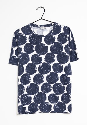 Witte T-shirt met korte mouwen met grote onregelmatige navyblauwe ronde patronen, hangend aan een zwarte hanger tegen een witte achtergrond.