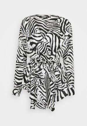 Langærmet sort-hvid zebra-print slå-om bluse med V-hals og bindebælte i taljen.