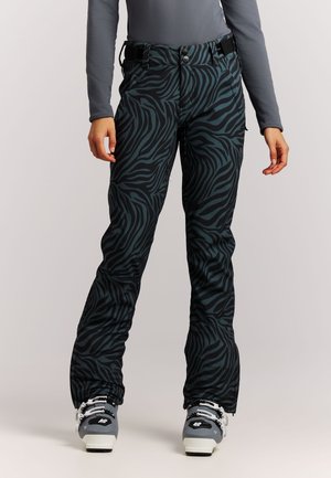 Person trägt schwarze und dunkelgrüne, zebragestreifte Skihose mit grauen Skischuhen und ein eng anliegendes graues Langarmshirt.