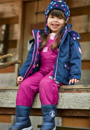 Completo invernale per bambini: giacca blu con cappuccio e dettagli rosa, salopette viola e stivali blu con logo circolare, seduti su una panchina di legno.