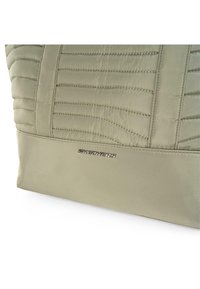 Bolso de tela acolchada verde claro con un panel inferior liso. Presenta detalles de costura sutiles y un logo plateado de "SKECHERS". Diseño acentuado.