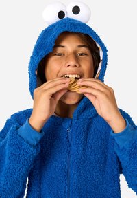 Modra puhasta pidžama s kapuco, ki ima velike bele in črne oči. Oblačilo ima zadrgo in rebraste manšete, nosi pa se ob držanju piškotov.