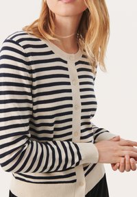 Navy a krémový pruhovaný cardigan s kulatým výstřihem, zapínáním na knoflíky a žebrovanými manžetami. Pletený materiál vykazuje jemnou strukturu.