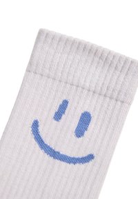 Hvit bomullssokk med ribbet tekstur som har et blått smilefjes-design på mansjetten, som fremhever et lekent mønster.