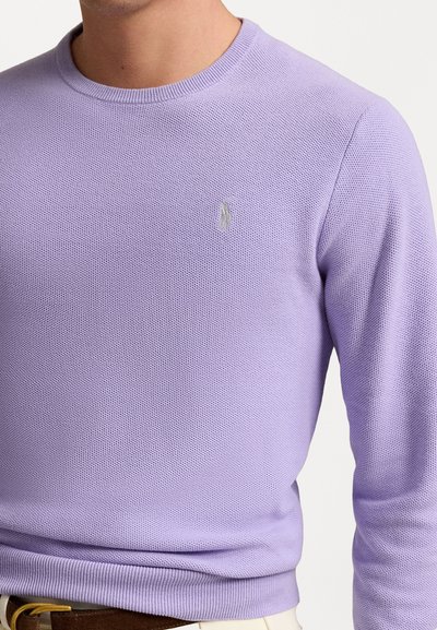 Lilla crew-neck sweater med et tekstureret strikkemønster. Har et lille, broderet logo på brystet samt rib kant detaljer ved ærmer og søm.