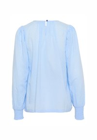 Blouse à manches longues bleu clair en tissu texturé, ornée de manches bouffantes, d'une fermeture en keyhole au dos et de poignets élastiques.