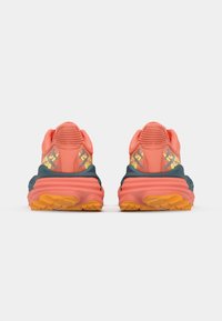Athletic shoes featuring a pink upper with yellow accents, a dark blue sole, and textured patterns on the back and sole for traction.