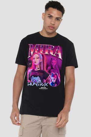 Junger Mann trägt ein schwarzes T-Shirt mit lebendigen violetten und pinkfarbenen animierten Figuren sowie den Texten "MIRA" und "HUNTRX" auf der Vorderseite, beige Shorts.