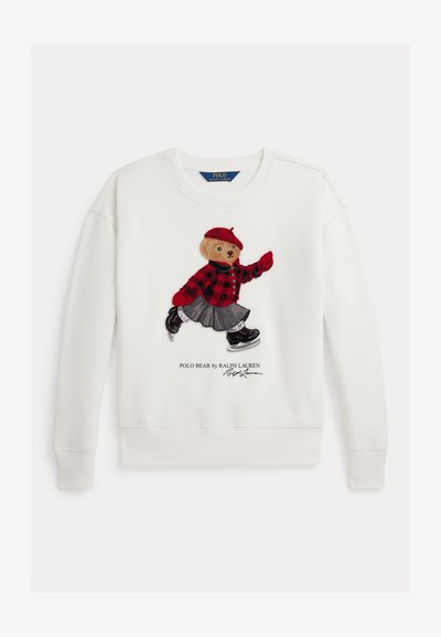 Fehér pulóver, amelyen egy hímzett mesebeli medve látható piros kockás ingben, szürke szoknyában és fekete cipőben, a minta alatt logószöveggel.