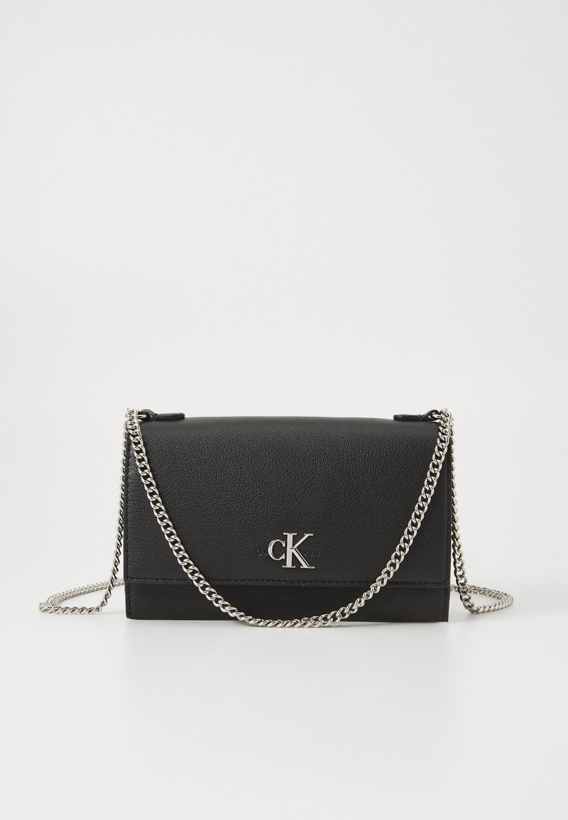 Borsa a tracolla in pelle nera con una tracolla in catena argentata, caratterizzata da un design a pieghe e un logo "CK" in rilievo sulla parte anteriore.