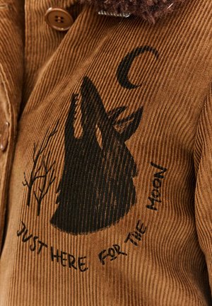 Brązowa kurtka z korduroju z sylwetką czarnego wilka i wzorem drzew, z napisem "Tylko tu dla księżyca" poniżej.