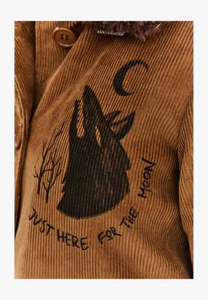 Brązowa kurtka z korduroju z sylwetką czarnego wilka i wzorem drzew, z napisem "Tylko tu dla księżyca" poniżej.