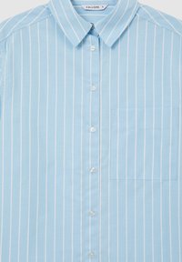 Chemise bleu clair à boutons avec des rayures blanches verticales et une poche poitrine côté droit, à col pointu et petits boutons blancs.