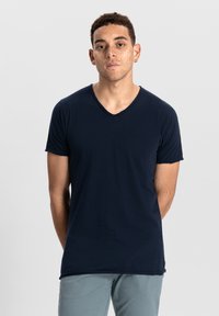 Námořnická modrá v-neck tričko vyrobené z měkké látky s krátkými rukávy, s úzkým střihem a nenápadným designem bez vzorů nebo zdobení.