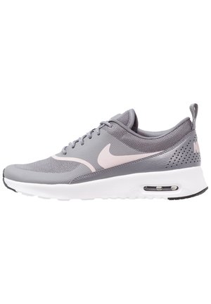 Chaussure de course Nike grise et rose avec dessus en mesh, fermeture à lacets, semelle blanche amortie et unité d'air visible au talon, vue de côté.