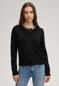 Μαύρο ζακέτα από υφασμάτινη ύφανση, με στρογγυλή λαιμόκοψη διακοσμημένη με διάφανα πετράδια, πλήρες κούμπωμα με κουμπιά και ριμπ μανσέτες και τελείωμα.