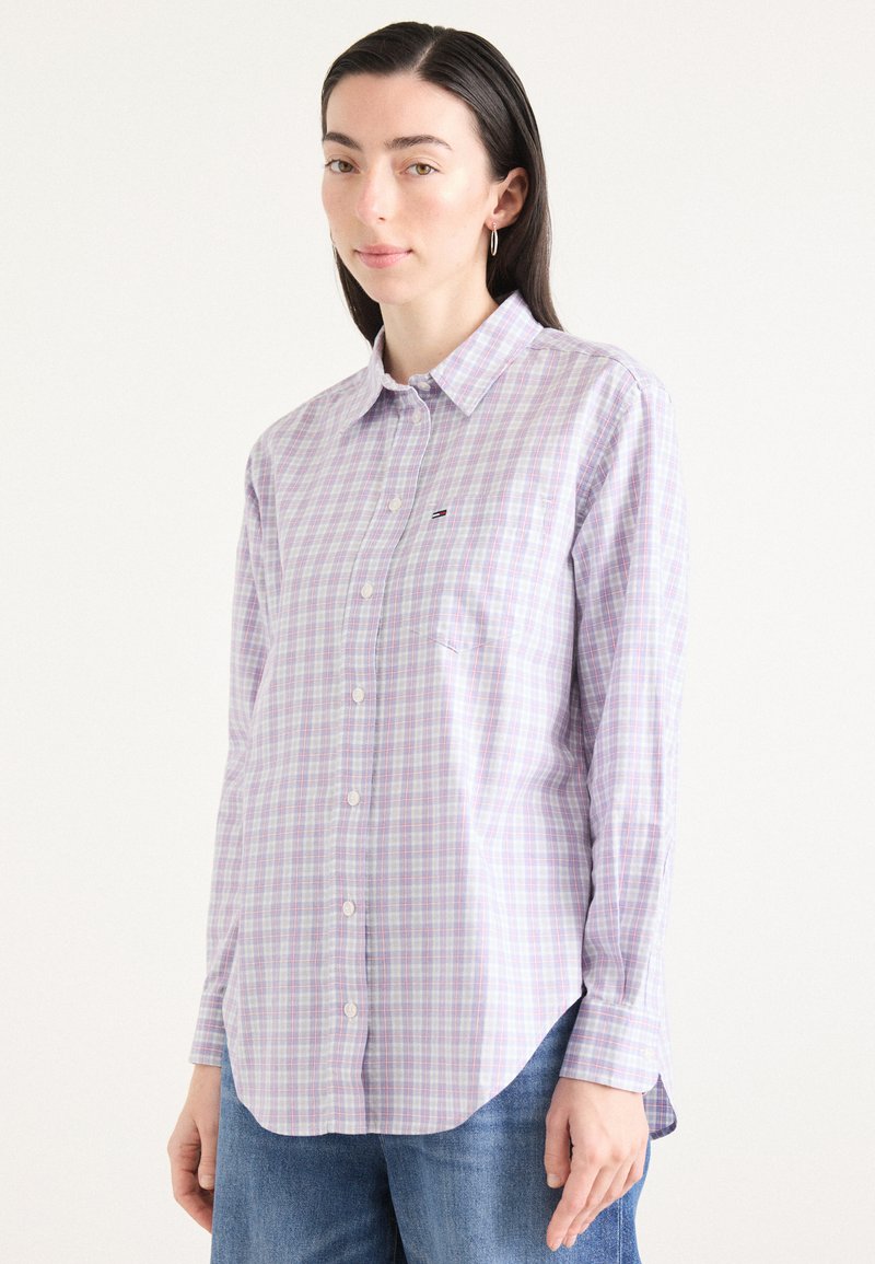 Button-up shirt in light purple and white check pattern; features a collar, long sleeves, and a small pocket on the chest.