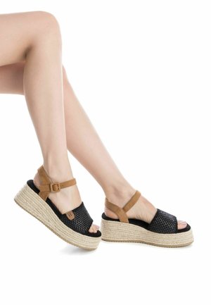 Sandalias de plataforma tejidas negras con correas de ante en tono beige, presentan una suela de yute estilo espadrille y hebilla ajustable en el tobillo.