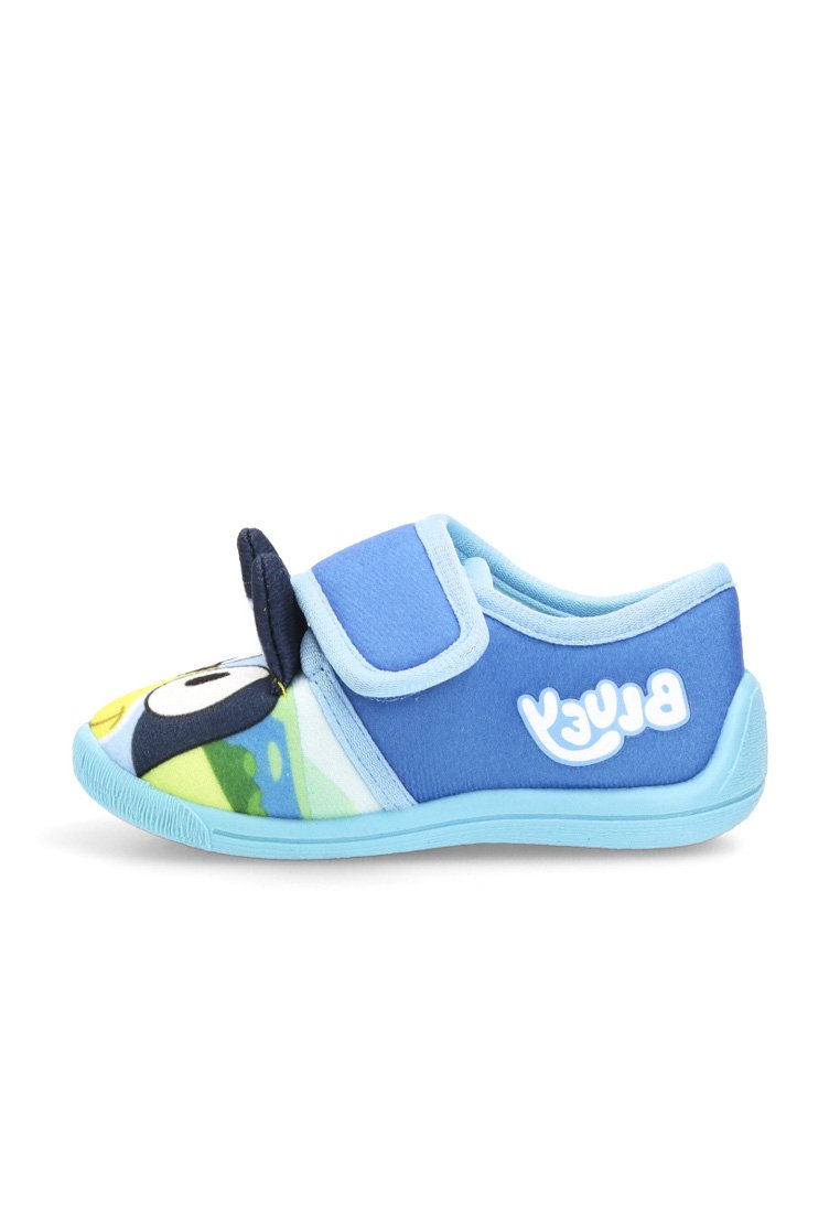 Zapatilla infantil azul con cinta de velcro, cara de pingüino de dibujos animados en la punta y texto "Bluey" en el lado, sobre fondo blanco.