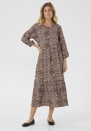 Rochie maxi cu imprimeu leopard în bej cu pete negre, având un design în straturi, mâneci lungi și decolteu rotund. Asortată cu pantofi negri.