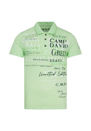 La camisa polo de rayas verdes cuenta con un collar, tres botones y diversos diseños impresos y textos en colores contrastantes a lo largo de la tela.